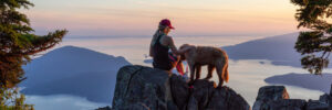 Woman sitting on mountain peak with her dog